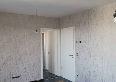 Tapétázott nappali világos mintás falburkolattal és fehér mennyezettel